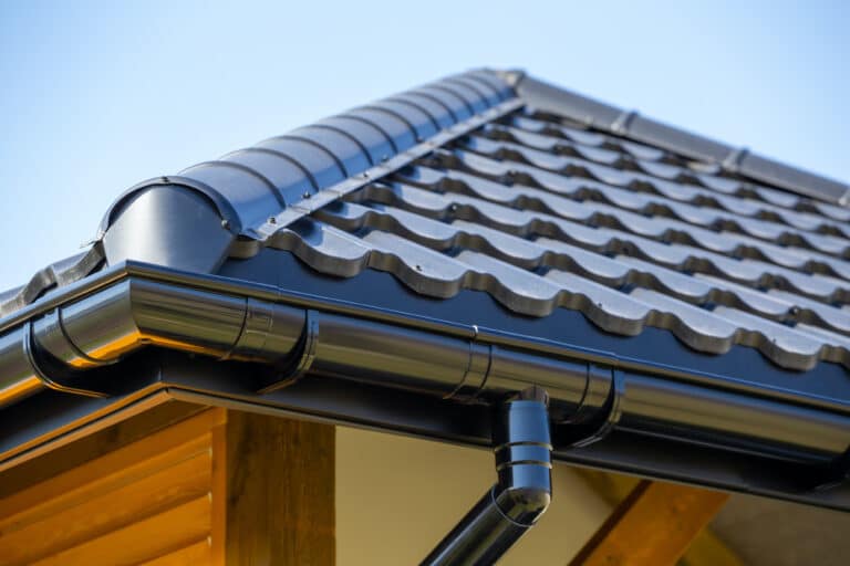 Corner of the new modern house with roof, gutter and wooden shutter under blue sky